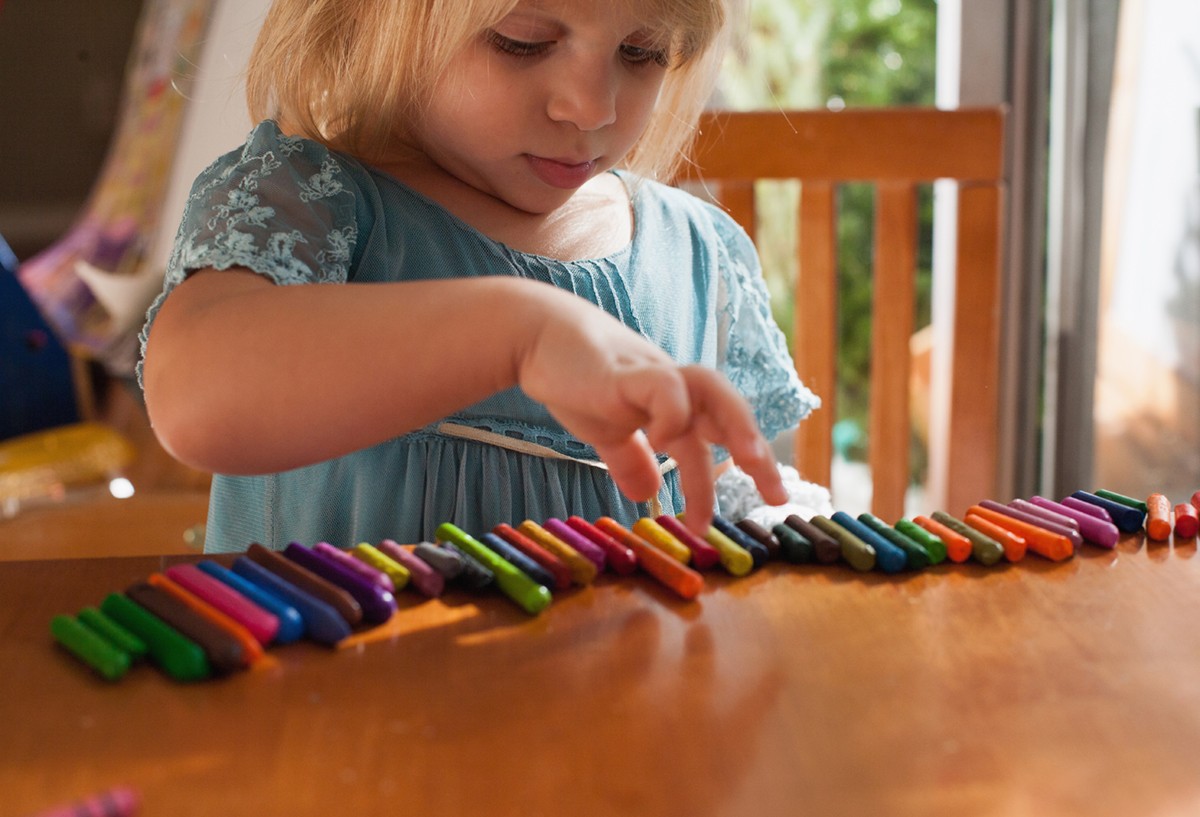 Toddler lining up crayons in a row