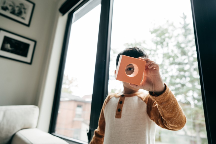 Boy standing in front of window looking through building block